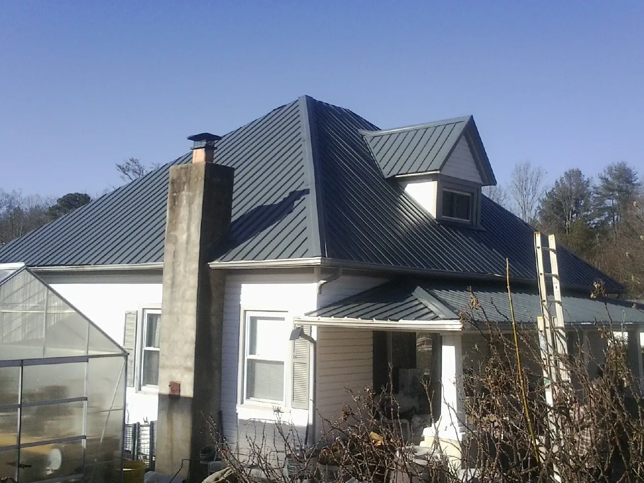 Dark blue standing seam metal roof on a white farmhouse with dormer — Slate & Tile Roof Repair by Roofing Brothers in Stem