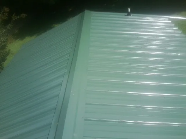New green metal panels meeting at the ridge of a roof — Flat Roof Repair work by our crew in Stem