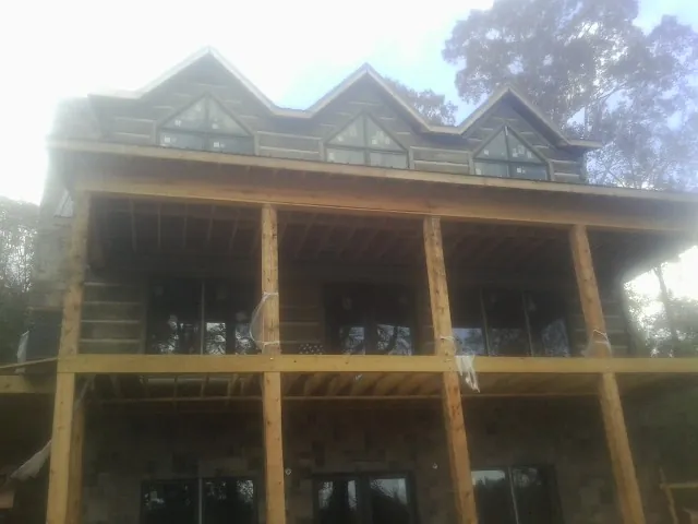 Dormers and porch framing on a large log home under construction — Roof Coating work by our crew in Stem