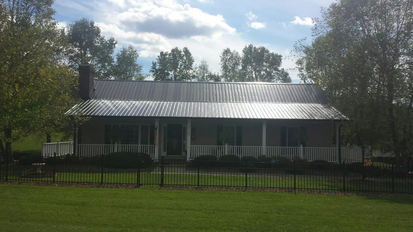 Gray metal roof on a brick ranch with a full width front porch — Gutter Guard Installation work by our crew in Stem