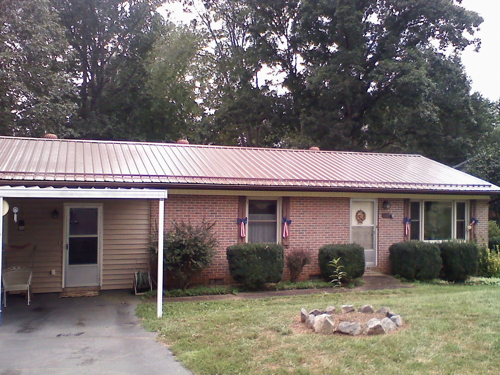Bronze metal roof and carport on a brick ranch home — Roof Repair work by our crew in Stem
