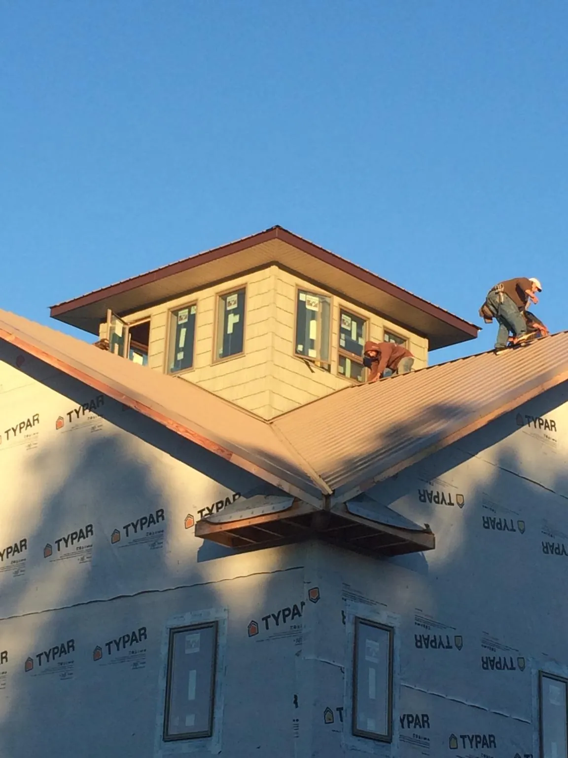 Roofers working around a rooftop cupola on a new metal roof at sunset — Roof Waterproofing in Stem by Roofing Brothers